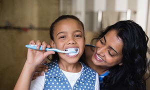 a parent teaching their child how to brush their teeth