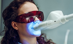 Woman having professional teeth whitening treatment