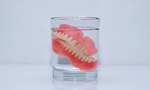 Dentures soak in glass of liquid
