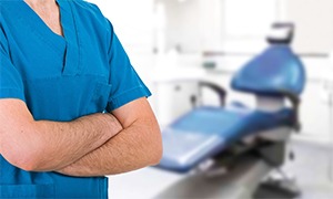Dentist standing with arms crossed in dental exam room