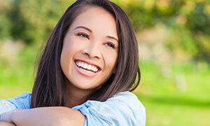 Woman with long dark hair smiling outdoors