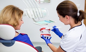 Happy female dentist and patient discussing denture care