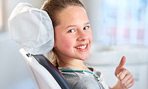 Child giving thumbs up in dental chair