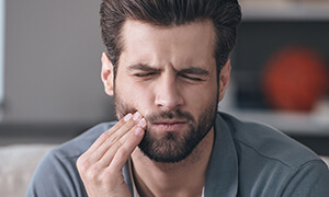 Man holding his cheek in pain