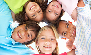 Group of smiling children putting their heads together in circle formation