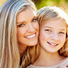 Mother and daughter smiling outdoors after dental services in Metairie