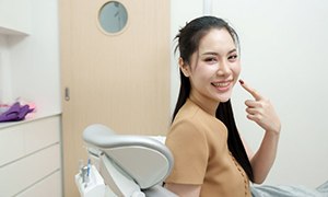 Happy dental patient pointing at her smile