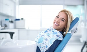 Woman in dental chair smiling after teeth whitening in Metairie