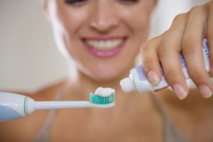 A woman putting toothpaste on a toothbrush.