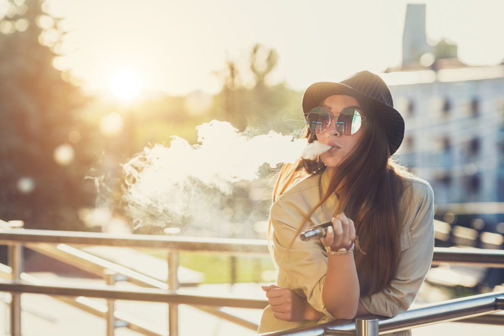 woman vaping on a bridge