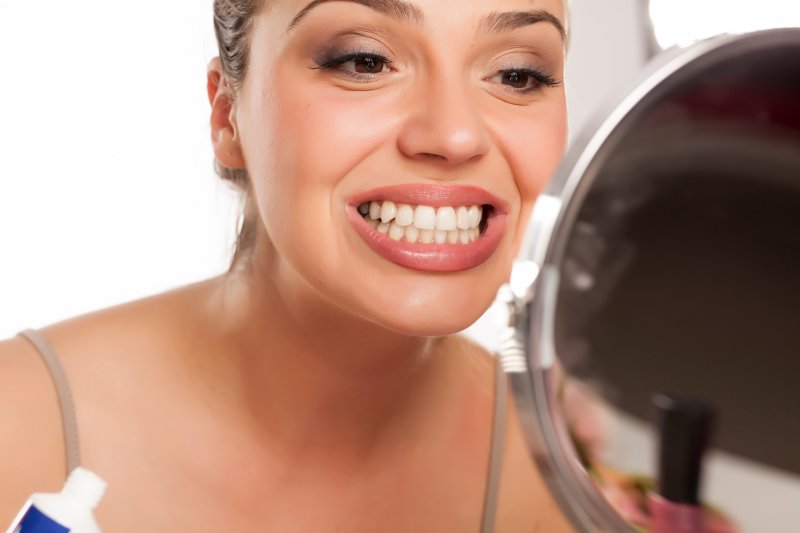 person checking their teeth in a mirror