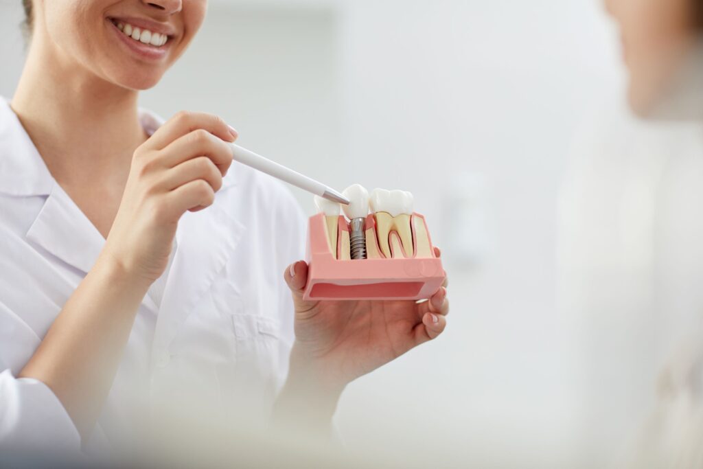 Dentist pointing to sample dental implant to show patient