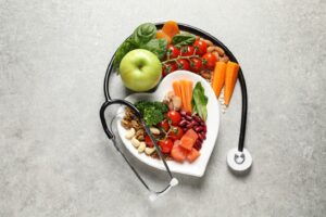 Healthy foods in heart-shaped bowl with stethoscope laid over it.